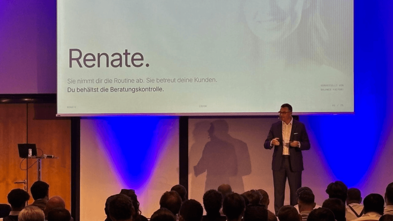 A speaker on stage presenting the opening slide of the Renate voice agent to an audience.